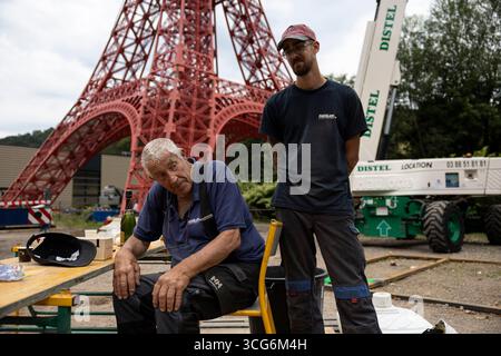 Sainte Marie Aux Mines, Frankreich. August 2025. Jean-Claude Fassler (l) und sein Enkel Kilian stehen vor dem Nachbau des Eiffelturms. Eine Kopie des Eiffelturms wird im Elsass seit acht Jahren gebaut. Ein Metallarbeiter hat den Nachbau im Elsass an der deutschen Grenze im Maßstab 1:10 gebaut, aber der Turm ist noch 30 Meter hoch. Quelle: Hannes P. Albert/dpa/Alamy Live News Stockfoto