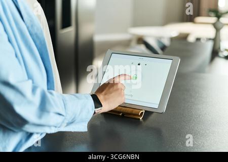 Kaukasische junge Erwachsene Frau mit digitalem Tablet mit Sicherheitsschloss-Symbol auf dem Bildschirm, berührendem Display, während sie an der Küchentheke steht und sich auf Technologie und Datenschutz konzentriert Stockfoto