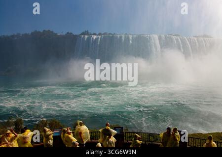 Eine Gruppe von Touristen und die beeindruckenden American Falls und die Rainbow International Bridge in Buffalo, Niagara River, Niagara Falls, Ontario, Kanada Stockfoto