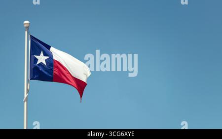 Die Texas State Flagge auf dem Pol winkt im Flügel gegen den hellblauen Himmel Stockfoto