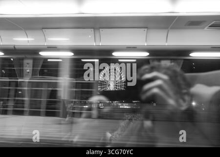 Nachtansicht durch ein Zugfenster mit Innenspiegelung und dem Rinku No Hoshi Riesenrad, Osaka, Kansai, Honshu, Japan Stockfoto