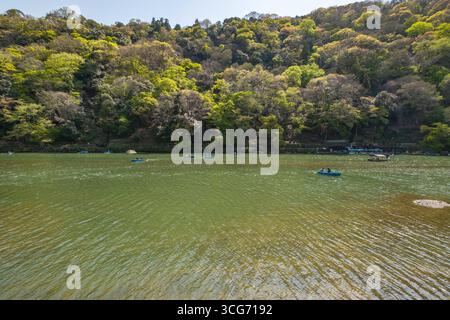 Touristen rudern kleine Ruderboote im Fluss Katsura an einem sonnigen Tag im April, Arashiyama, Ukyo Ward, Kyoto, Kansai, Honshu, Japan Stockfoto