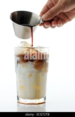 Geben Sie Espresso auf ein Glas Milch und verarbeiten Sie Eiskaffee-Espresso. Isoliert auf weiß Stockfoto