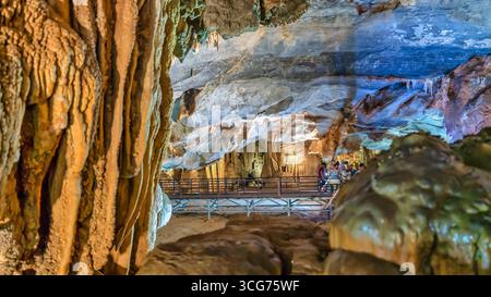 Touristen besuchen auf hölzernen Gehweg durch die malerische Natur Flur Paradies Höhle mit Stalaktiten und Stalagmiten in Phong Nha National Park, Quang Binh Stockfoto