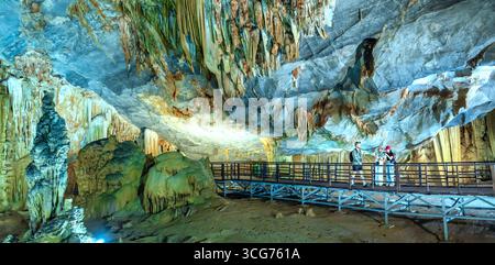 Touristen besuchen auf hölzernen Gehweg durch die malerische Natur Flur Paradies Höhle mit Stalaktiten und Stalagmiten in Phong Nha National Park, Quang Binh Stockfoto