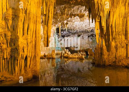 Stalaktiten und Stalagmiten im Inneren der Neptungrotte, Capo Caccia, Sardinien, mit ruhigem Wasser, das die atemberaubenden Formationen der Höhle reflektiert. Stockfoto
