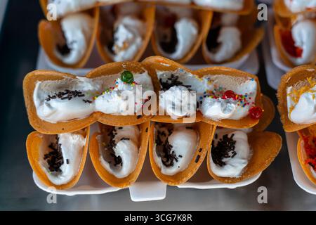 Köstliche thailändische Straße Dessert, Kanom Buang, Thai knusprige Pfannkuchen oder Thai Krepp, mit verschiedenen Füllungen wie süß weiß Pudding Sahne und golden Stockfoto