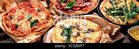 Italienische Pizza auf rustikalem Holztisch, Blick von oben, große Komposition. Frisch zubereitete Pizza, gebacken mit Kräutern und Gemüse, Meeresfrüchten, Fleisch. Stockfoto