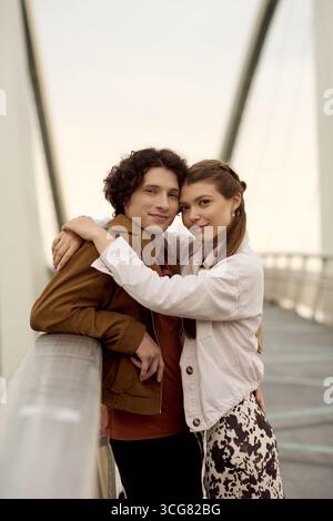 Das junge Paar umarmt sich auf einer Brücke und teilt einen Moment der Zuneigung und Wärme zusammen. Stockfoto