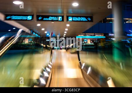 Beleuchteter Flughafen Zürich mit Eskalator in unscharfer Bewegung bei Nacht im Flughafen Kloten, Zürich, Kanton Zürich, Schweiz. Stockfoto