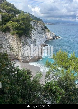 Felsige Klippen mit Kiefern und ein versteckter Kieselstrand entlang der Küste von Kreta, Griechenland. Stockfoto