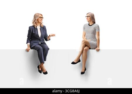 Zwei Frauen, die auf einem Panel sitzen und ein Gespräch auf weißem Hintergrund führen Stockfoto