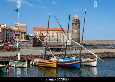 Vor der Kirche Notre-Dame-des-Anges rastet der katalanische bob mit ihren Latineplattformen und hellen Rümpfen, die den ruhigen Kai und die Steinmauern von Collioure beleuchten Stockfoto