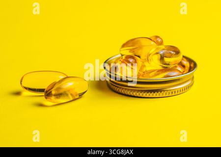 Gelbe Kapseln, Tabletten, Fischöl-Pillen liegen auf einem gelben Hintergrund. Vitaminkomplex Omega 3,6,9. Gesunde Nahrungsergänzungsmittel Stockfoto