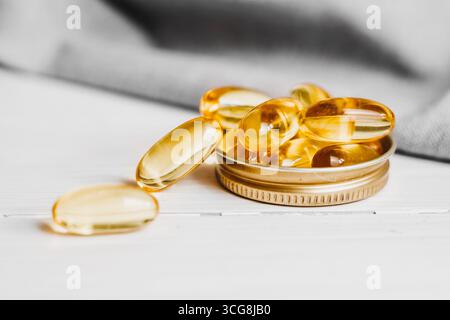 Gelbe Kapseln, Tabletten, Fischöl-Pillen liegen auf einem weißen Holztisch. Vitaminkomplex Omega 3,6,9. Stockfoto