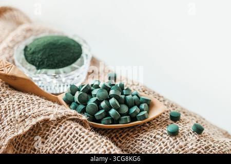 Spirulina Chlorella Tabletten auf einem Holzlöffel und Pulver in einer Glasschale. Kopierbereich. Detox Superfood Stockfoto