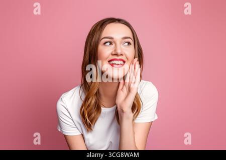Kaukasische junge Frau mit roten Lippen, die lächeln und schreien, isoliert über rosa Hintergrund im Studio Stockfoto
