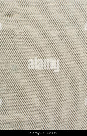 Blick von oben auf cremefarbenen Strickstoff, Nahsicht auf strukturierten Strickstoff Stockfoto