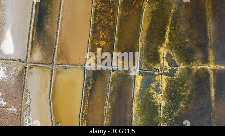 Aus der Vogelperspektive sehen Sie das Mosaik der farbenfrohen Salinen, deren Strukturen stark gegen den klaren Adriahimmel sind und eine surreale Landschaft schaffen, Pag, Kreis Zadar, Kroatien. Stockfoto