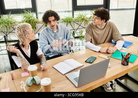 Drei junge Menschen nehmen an einem lebhaften Arbeitsplatz an einer gemeinsamen Diskussion teil. Stockfoto