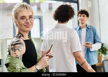Drei junge Fachkräfte führen produktive Gespräche, während sie im Büro fleißig arbeiten. Stockfoto