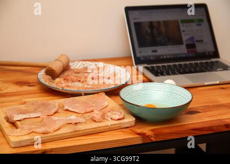 Ein schönes und elegantes Konzept einer gesunden Küche. Gesunde Mahlzeit Vorbereitung Laptop Rezept. Kochprozess von Hähnchenrezept-Laptop. Hausmannskost Stockfoto