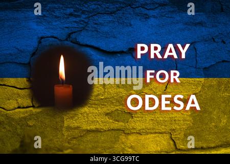 Ein kraftvolles und düsteres Bild einer ukrainischen Flagge und einer Kerze in Odesa, in einer Geste der Trauer nach dem Beschuss Russlands. Ukrainische Flaggentrauer Stockfoto