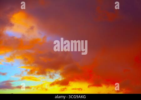 Der Himmel leuchtet mit lebhaften Wolken und fängt das Licht einer aufgehenden oder untergehenden Sonne ein. Ein weicher Farbverlauf von Gelb zu Blau in der Nähe des Horizonts sorgt für Tiefe und Wärme Stockfoto