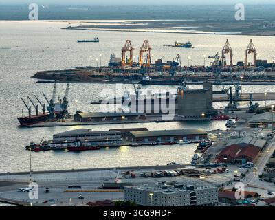 Thessaloniki, Griechenland 3. August 2025. Drohnenansicht des Handelhafens mit Frachtschiffen, Kränen und der städtischen Uferpromenade am Thermaischen Golf Stockfoto