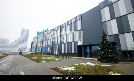 Weißrussland, Minsk - 26, 12, 2024: Es gibt ein großes, beeindruckendes Gebäude, das prominent steht, und davor steht ein wunderschön dekoriertes Weihnachtsfest Stockfoto