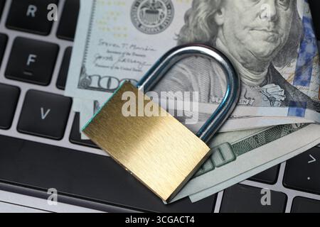 Cyber-Sicherheit. Vorhängeschloss aus Metall und Dollar auf Laptop, Blick von oben Stockfoto
