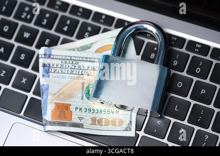 Cyber-Sicherheit. Vorhängeschloss aus Metall und Dollars auf Laptop, Aussicht über dem Zimmer Stockfoto