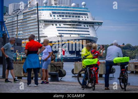Wismar, Deutschland. August 2025. Urlauber fotografieren das neue Kreuzfahrtschiff „Disney Adventure“ vom Stadthafen am ausgerüsteten Kai der Werft Wismar. Nach rund sieben Jahren Bauzeit wird eines der größten Kreuzfahrtschiffe der Welt in den nächsten Tagen die Hansestadt verlassen. Die US-Reederei Disney Cruise Line übernahm das Schiff vom Insolvenzgut und lässt es von der Meyer Werft in Papenburg, Niedersachsen, bauen. Das Schiff wird ab Ende 2025 für die Disney Group in Südostasien im Einsatz sein. Quelle: Jen/dpa/Alamy Live News Stockfoto