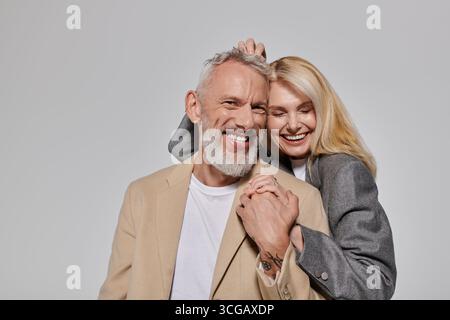 Ein liebevolles Seniorenpaar teilt einen fröhlichen Moment, gekleidet in stilvollen Outfits. Stockfoto