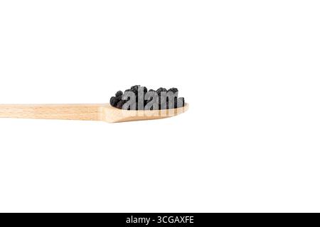 Getrocknete Aronia oder schwarze Aronia - Aronia melanocarpa auf lateinischem Holzlöffel isoliert auf weißem Hintergrund. Stockfoto