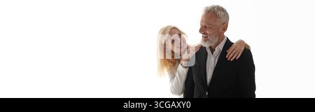 Ein fröhliches Seniorenpaar in eleganten Outfits teilt eine liebevolle Umarmung. Stockfoto