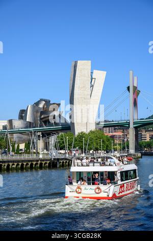 Ein Ausflugsboot auf dem Fluss Nervion mit der Salbeko Zubia Brücke, La Salve Brücke und dem Guggenheim Museum im Hintergrund, Bilbao, Baskenland, Nein Stockfoto