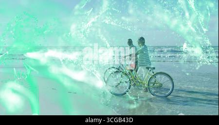 Stehender Mann und Frau mit Blick auf das Meer am Strand, mit Fahrrädern und grünem digitalem Netzwerk Stockfoto