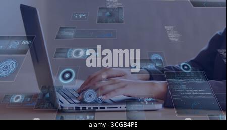 Eine Person mit dunklem Oberteil, die mit holografischen Code-Overlays auf dem Laptop am Schreibtisch interagiert Stockfoto