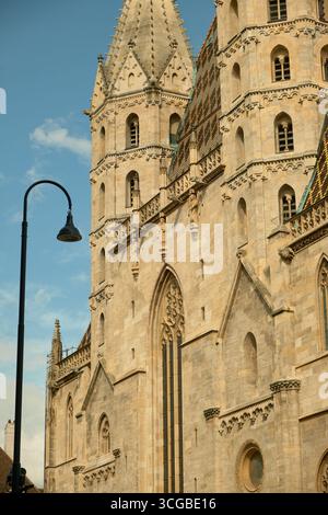 Ein Seitenblick auf den Stephansdom in Wien mit zwei seiner hohen Türme und komplizierten gotischen Details. Eine klassische Straßenlaterne steht für mich Stockfoto