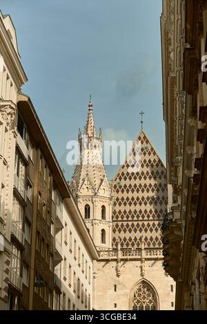 Ein Blick auf den Stephansdom und das ikonische Mosaikdach, eingerahmt von den klassischen Fassaden der Altstadtgebäude in Wien, schaffen einen wunderschönen Stockfoto