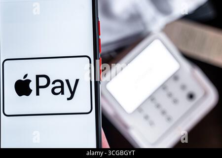 Bayern, Deutschland - 27. August 2025: Ein Smartphone mit dem Apple Pay Logo vor einem EC-Terminal in einem Geschäft *** ein Smartphone mit Apple-Pay-Logo vor einem EC-Terminal im Geschäft Stockfoto