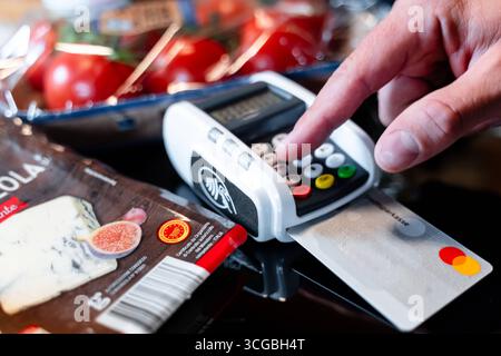 Bayern, Deutschland - 27. August 2025: Ein Kunde bezahlt seine Lebensmittel im Supermarkt mit einer Kreditkarte und gibt die PIN am Terminal ein *** ein Kunde bezahlt seinen Lebensmitteleinkauf im Supermarkt mit einer Kreditkarte und gibt die PIN am Terminal ein Stockfoto