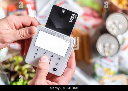 Bayern, Deutschland - 27. August 2025: Ein Kunde bezahlt Lebensmittel in einem Supermarkt mit einer Kreditkarte. Symbolisches Foto für bargeldlose Kartenzahlungen, moderne POS-Systeme und digitale Zahlungen im Einzelhandel. *** Ein Kunde bezahlt Lebensmittel im Supermarkt mit Kreditkarte. Symbolfoto für bargeldlose Kartenzahlung, moderne Kassensysteme und digitales bezahlen im Einzelhandel. Stockfoto