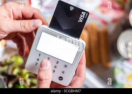Bayern, Deutschland - 27. August 2025: Ein Kunde bezahlt Lebensmittel in einem Supermarkt mit einer Kreditkarte. Symbolisches Foto für bargeldlose Kartenzahlungen, moderne POS-Systeme und digitale Zahlungen im Einzelhandel. *** Ein Kunde bezahlt Lebensmittel im Supermarkt mit Kreditkarte. Symbolfoto für bargeldlose Kartenzahlung, moderne Kassensysteme und digitales bezahlen im Einzelhandel. Stockfoto