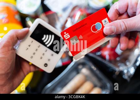 Bayern, Deutschland - 27. August 2025: FOTOMONTAGE, Ein Kunde zahlt für seinen Lebensmitteleinkauf im Supermarkt kontaktlos mit einer EC-Karte *** FOTOMONTAGE, ein Kunde bezahlt seinen Lebensmitteleinkauf im Supermarkt kontaktlos mit einer EC-Karte Stockfoto