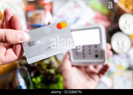Bayern, Deutschland - 27. August 2025: Ein Kunde zahlt seine Lebensmittel im Supermarkt kontaktlos mit einer Mastercard am EC-Terminal. Symbol Foto bargeldlose Zahlung, täglicher Verbrauch *** ein Kunde bezahlt im Supermarkt seinen Lebensmitteleinkauf kontaktlos mit einer Mastercard am EC-Terminal. Symbolfoto bargeldloses bezahlen, Konsum im Alltag Stockfoto