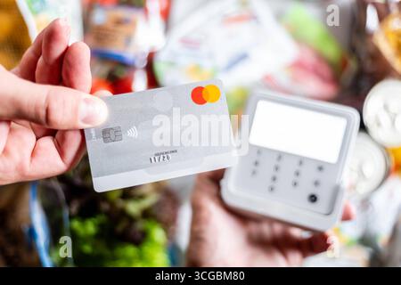 Bayern, Deutschland - 27. August 2025: Ein Kunde zahlt seine Lebensmittel im Supermarkt kontaktlos mit einer Mastercard am EC-Terminal. Symbol Foto bargeldlose Zahlung, täglicher Verbrauch *** ein Kunde bezahlt im Supermarkt seinen Lebensmitteleinkauf kontaktlos mit einer Mastercard am EC-Terminal. Symbolfoto bargeldloses bezahlen, Konsum im Alltag Stockfoto