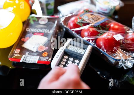 Bayern, Deutschland - 27. August 2025: Ein Kunde gibt seine PIN am Kartenleser an der Kasse des Supermarkts ein. Illustration bargeldloser Kartenzahlung beim Einkaufen von Lebensmitteln. *** Ein Kunde gibt an der Supermarktkasse seine PIN am Kartenlesegerät ein. Darstellung des bargeldlosen Bezahlens mit Karte beim Einkauf von Lebensmitteln. Stockfoto
