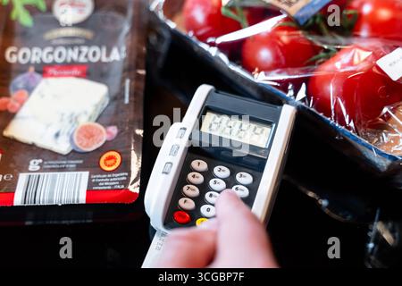 Bayern, Deutschland - 27. August 2025: Ein Kunde gibt seine PIN am Kartenleser an der Kasse des Supermarkts ein. Illustration bargeldloser Kartenzahlung beim Einkaufen von Lebensmitteln. *** Ein Kunde gibt an der Supermarktkasse seine PIN am Kartenlesegerät ein. Darstellung des bargeldlosen Bezahlens mit Karte beim Einkauf von Lebensmitteln. Stockfoto
